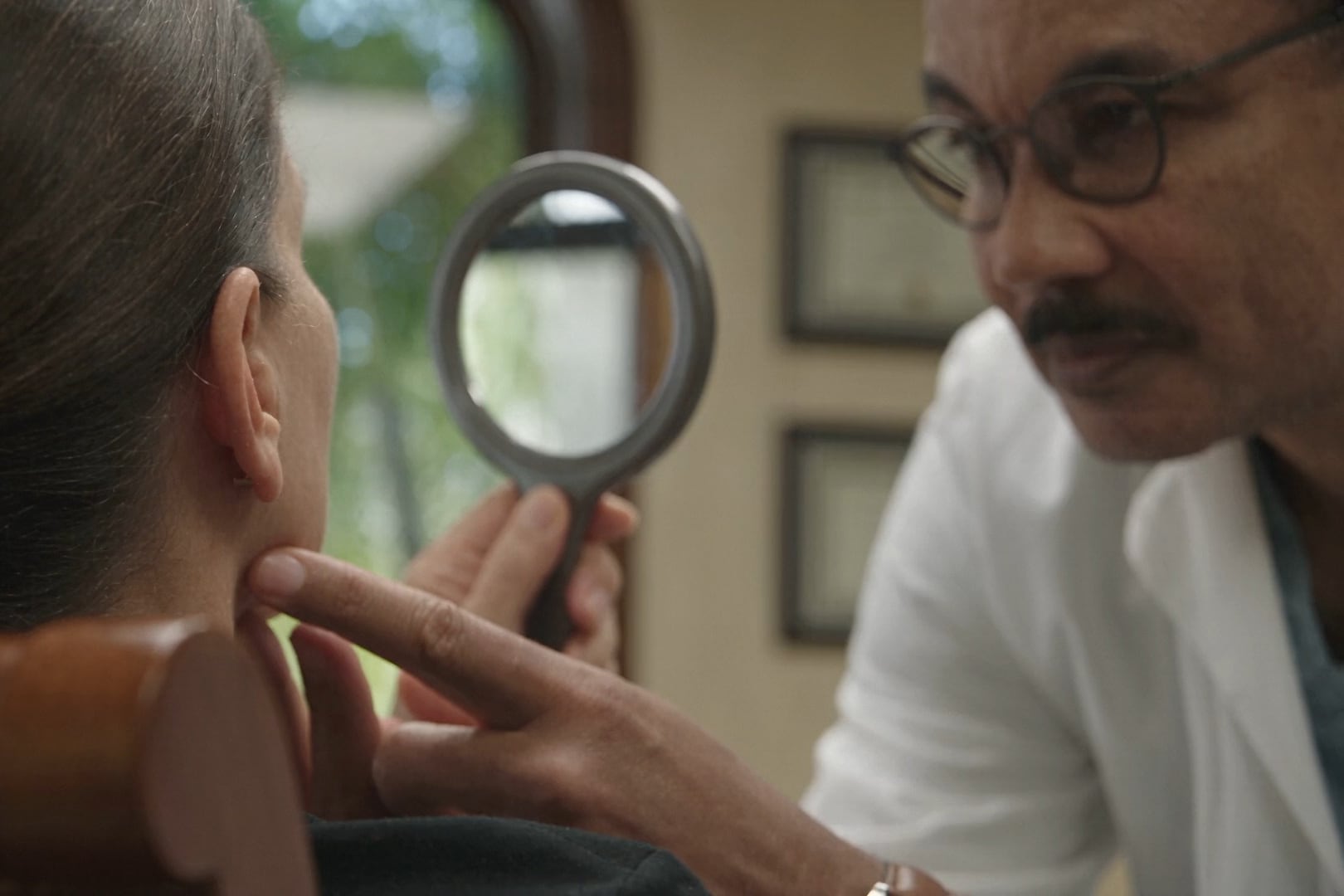 Dr. Kenrick Spence assessing a patient's profile while she holds a hand mirror