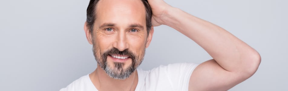 Stock photograph of a smiling bearded male model with a hand in his hair