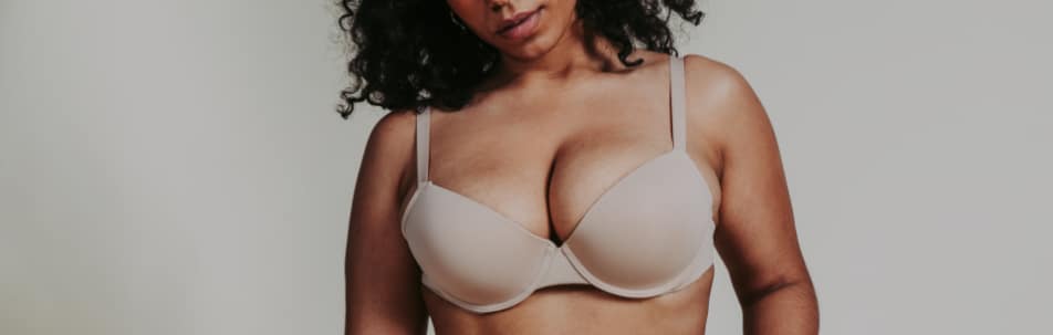 Stock photograph of a model in a beige bra, shown from the chin down