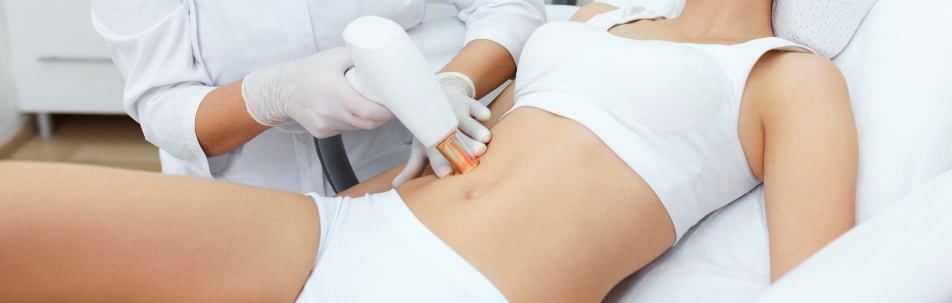 Provider in gloves holding a laser handpiece to a woman's abdomen during treatment